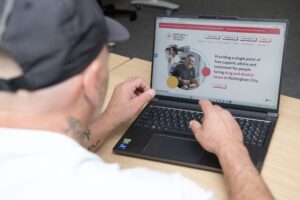 A man looking at the NRN website on a laptop