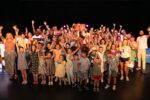 A group photo of all Framework's Young Supporters and staff holding up glow sticks